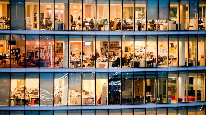 Arbeitsmarkt- und Sozialpolitik Mehrstöckiges, warm beleuchtetes Bürogebäude mit Glasfront