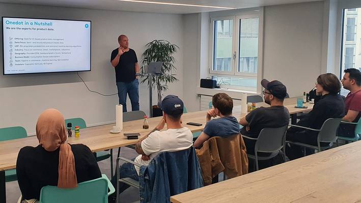 Meet up! Ein Referent hält einen Vortrag während eines Meet Ups bei einer Firma und die Studierenden hören interessiert zu.