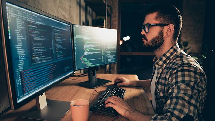 UX verringert Entwicklungskosten In der Weiterbildung UX Design wird auch die Zusammenarbeit mit Entwickler:innen gelernt: Mann sitzt am Computer.