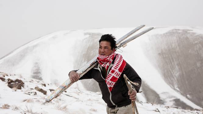 Distinguished Speaker Series (DSS) Person carrying a pair of ski in a snowy landscape