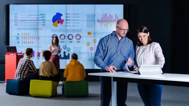 Masterstudienrichtung Data Visualization Data Visualization Masterstudierende mit Dashboard im Hintergrund