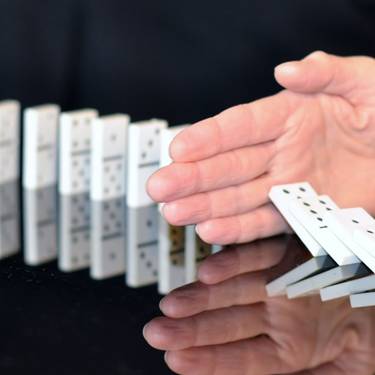 Header Integrity Talk Series Header, Hand hält umfallende Dominosteine auf